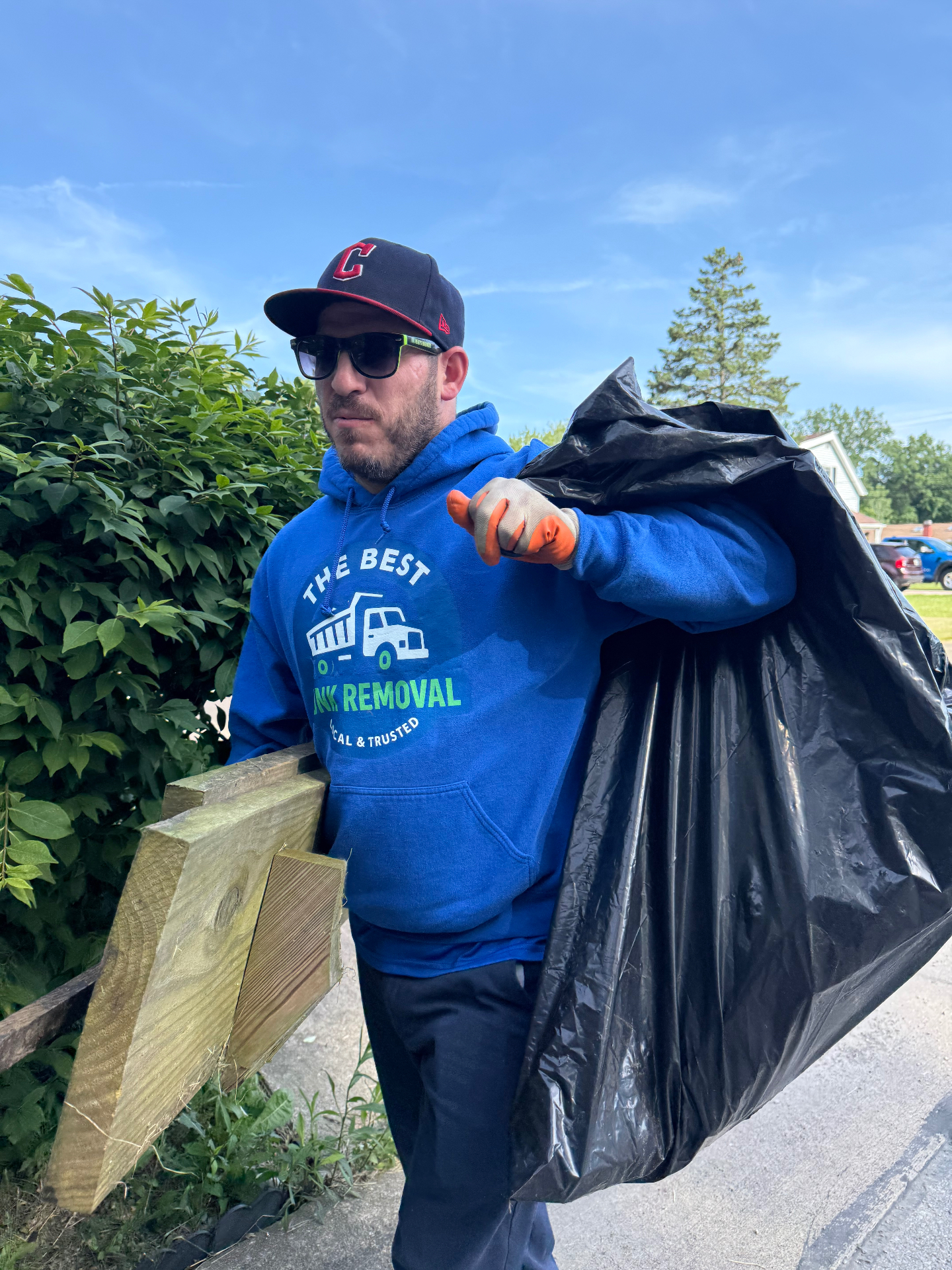 Andy, owner of The Best Junk Removal LLC, hauling heavy-duty contractor bags and scrap lumber to the curb during a same-day yard debris and junk cleanout in a Cleveland, Ohio suburb
