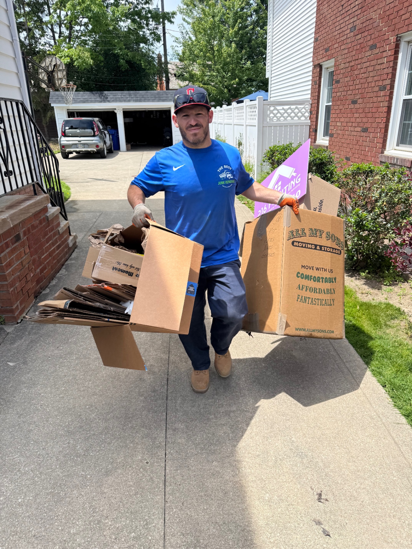 Andy from The Best Junk Removal LLC hauling broken-down cardboard boxes and moving-day debris out of a Cleveland, Ohio driveway — fast post-move cardboard and box removal serving Lakewood, Parma, and Strongsville